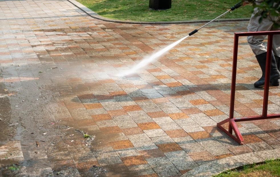Pressure washing dirty stone pavers with a bright water spray